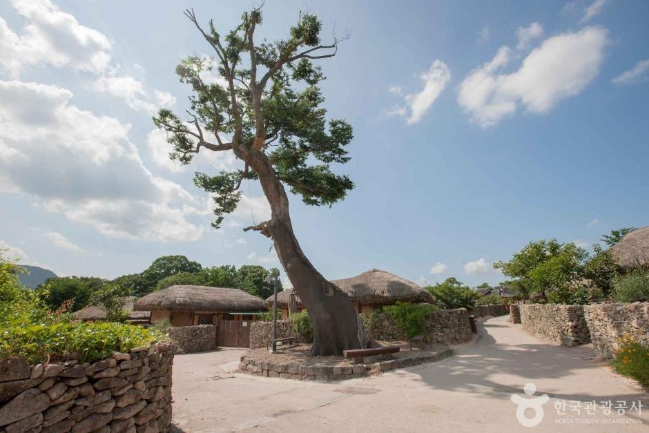 Traditional Korean thatched-roof houses along a stone wall path in Oeam Folk Village, Asan