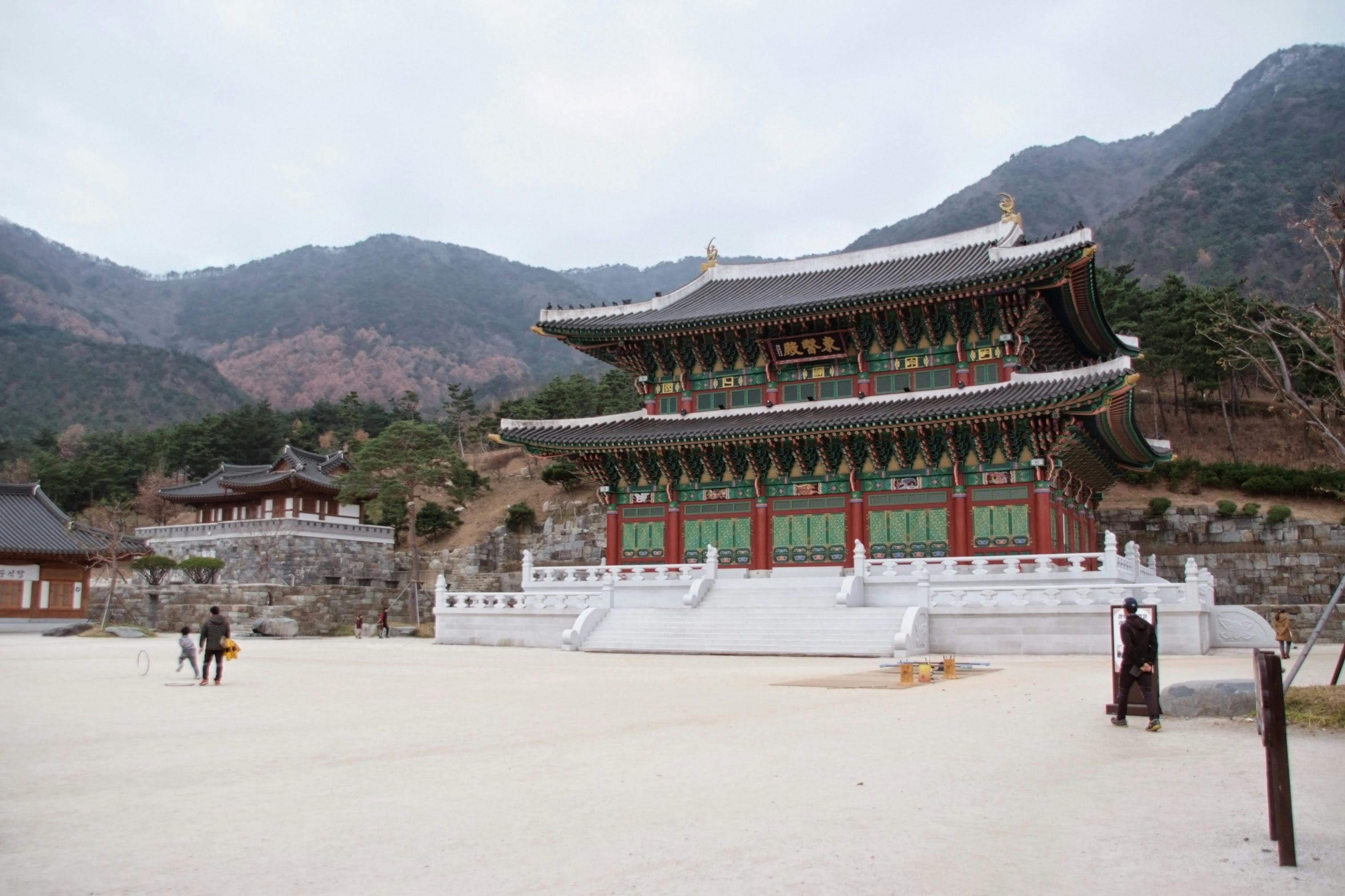 A traditional Korean temple with vibrant architecture set against a picturesque mountain backdrop