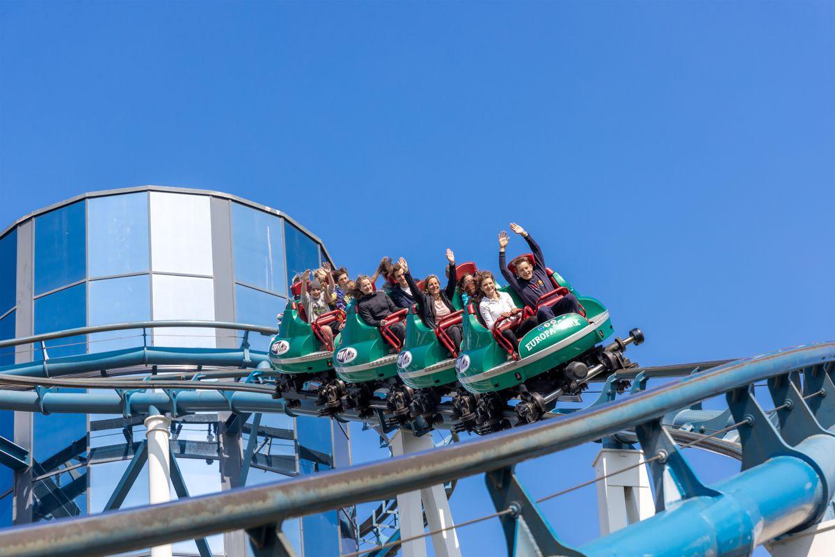 Visitors enjoying a summer theme park with colorful rides and green hills in Korea