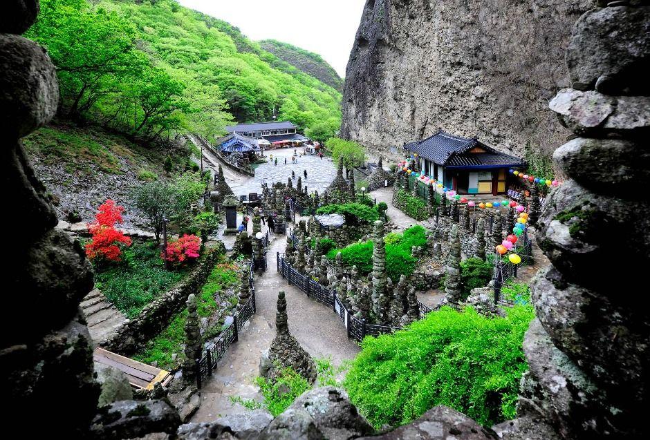 Bird's eye view of Tapsa's stone pagoda garden with colorful lanterns and traditional Korean temple building surrounded by the rocky peaks of Maisan