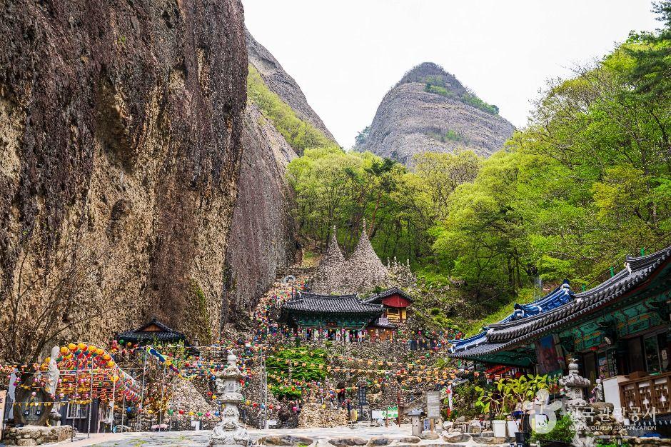 Ground-level view of Maisan's dramatic twin peaks with Tapsa Temple complex and stone pagodas visible below