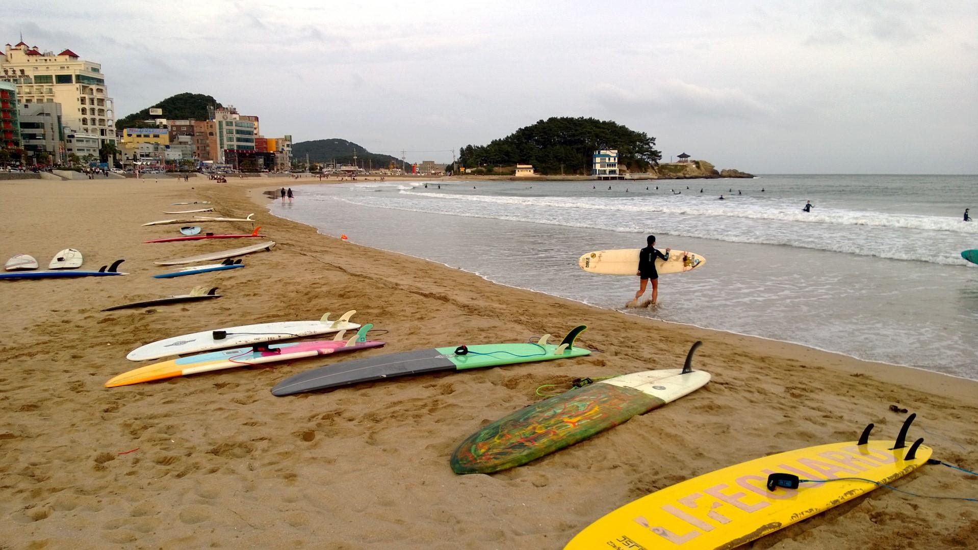 Songjeong Beach in Busan with surfers on a calm summer morning