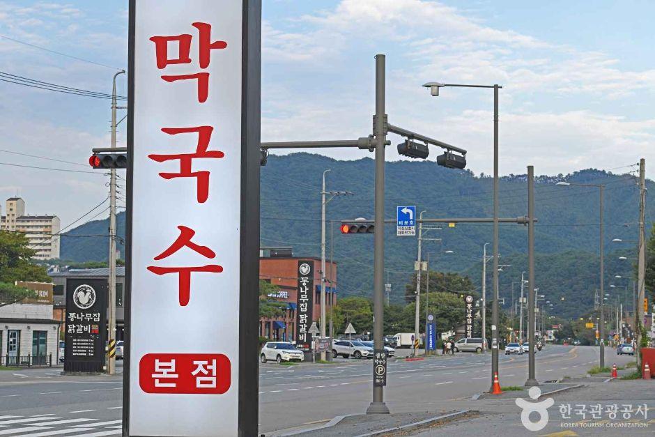 Traditional Korean makguksu restaurant near Soyang Lake with rustic wooden signage — the cold buckwheat noodle district along the lakeside road