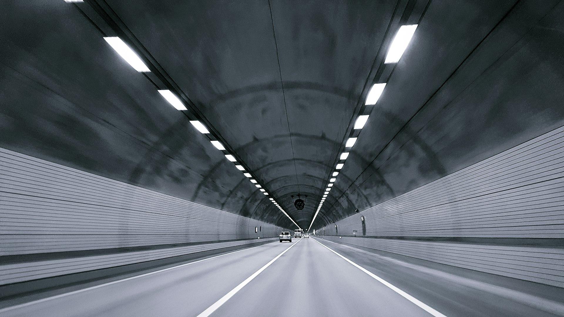 Car driving through a lit expressway tunnel in Korea