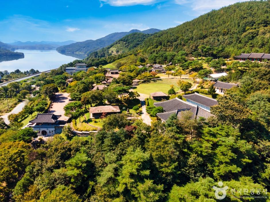 Traditional Korean hanok buildings at Munui Cultural Village with Daecheong Lake in the background