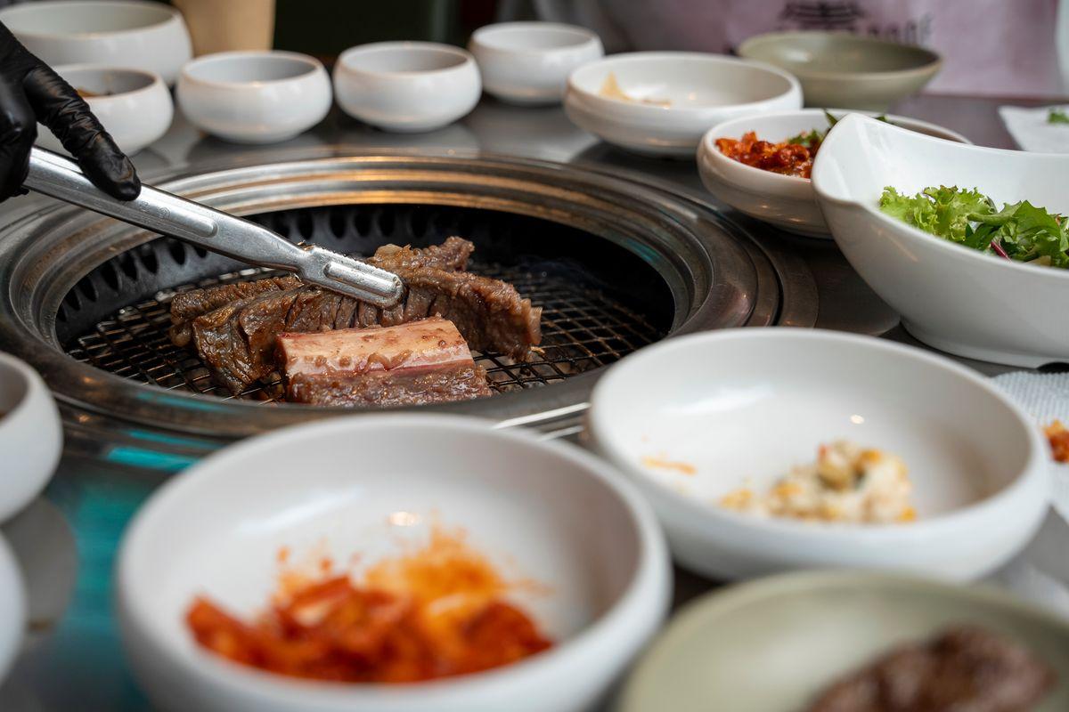 Traditional Korean pork ribs grilling on a tabletop grill with side dishes in a Korean restaurant