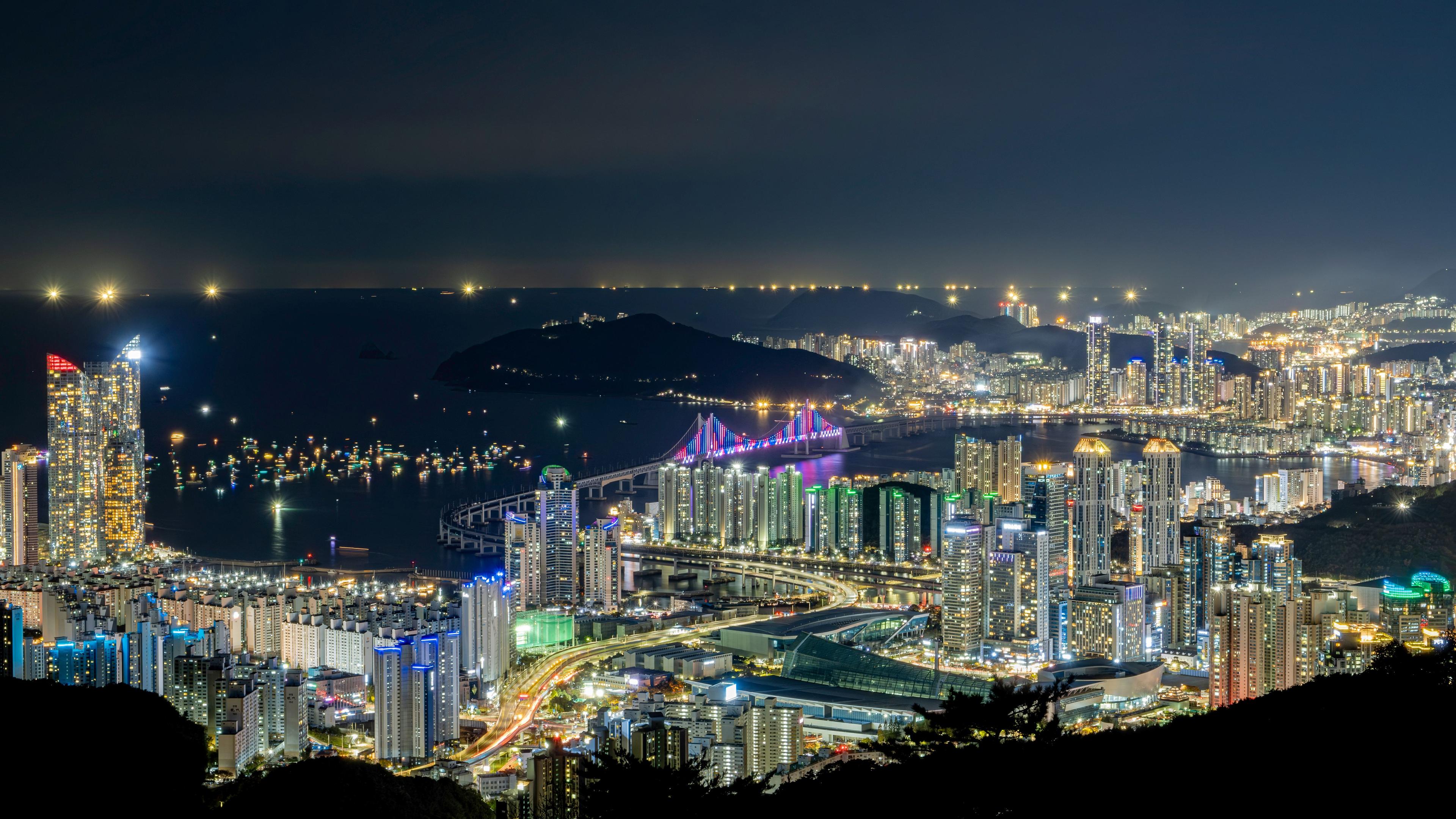 Gwangan Grand Bridge illuminated at night with colorful LED lights reflected in Gwangalli Beach, Busan