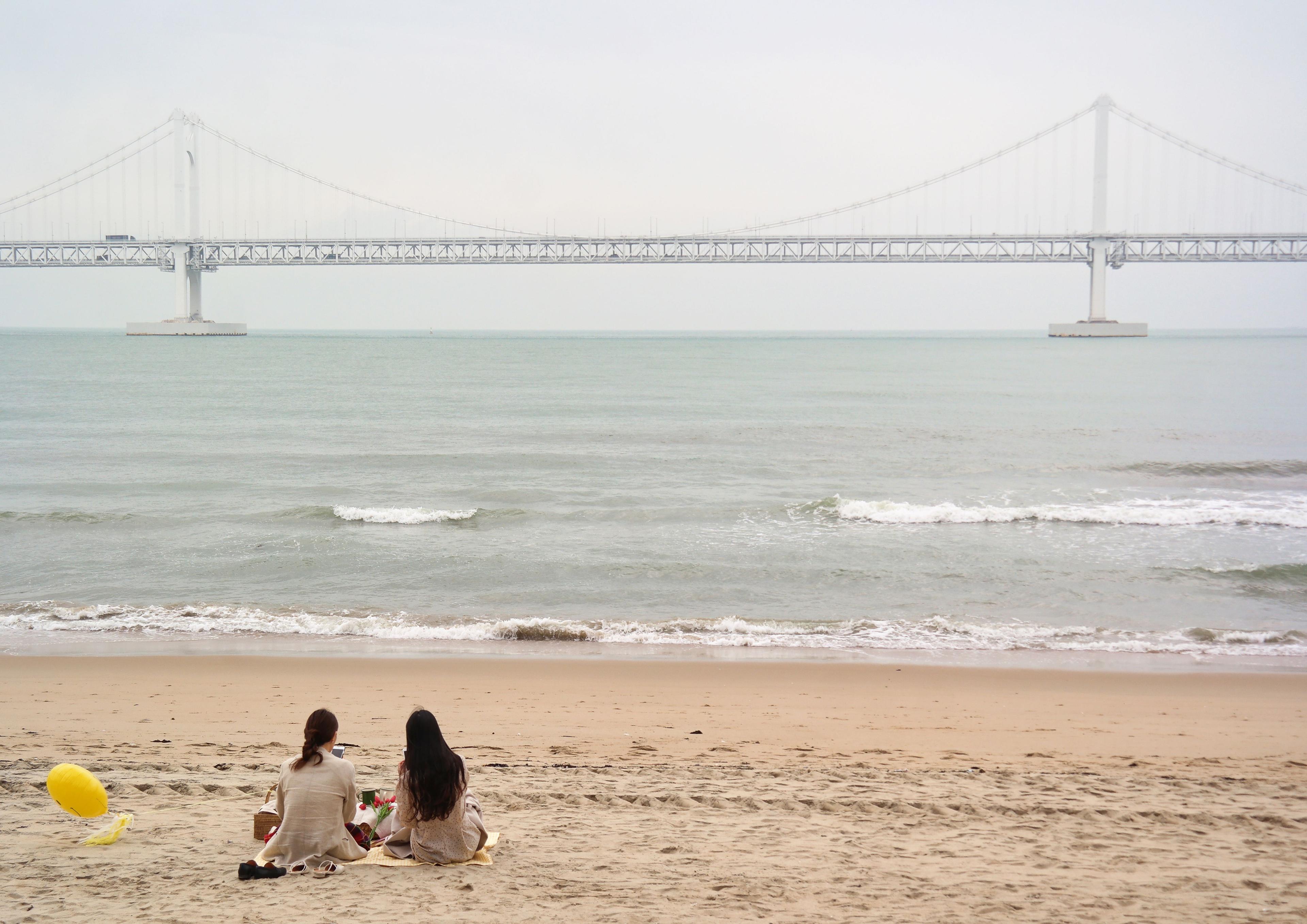 People swimming and relaxing on Gwangalli Beach in summer with clear blue water