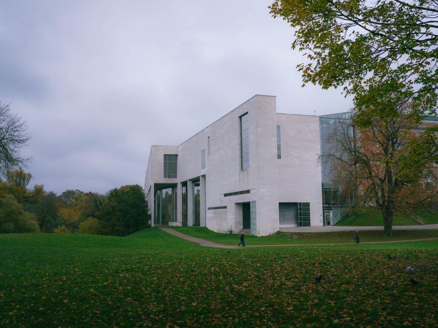 Modern museum building with curved architecture surrounded by green fields
