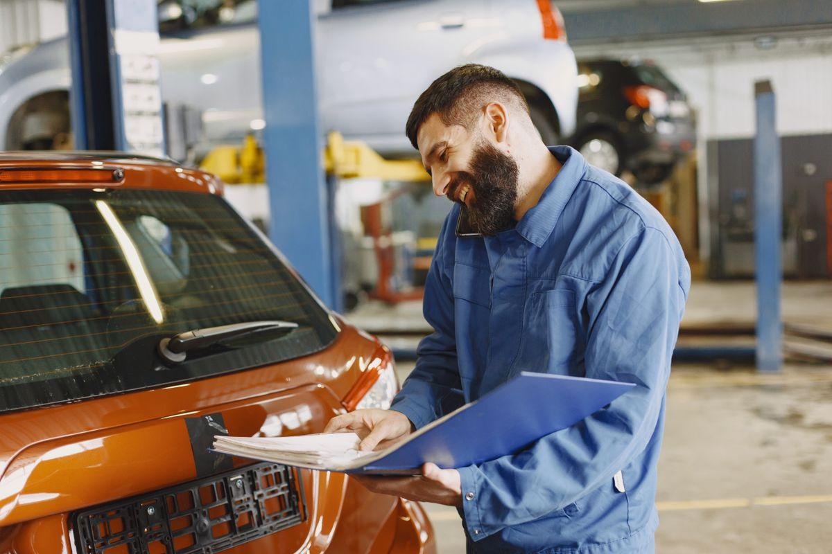 Staff member inspecting a rental car exterior during vehicle check-in