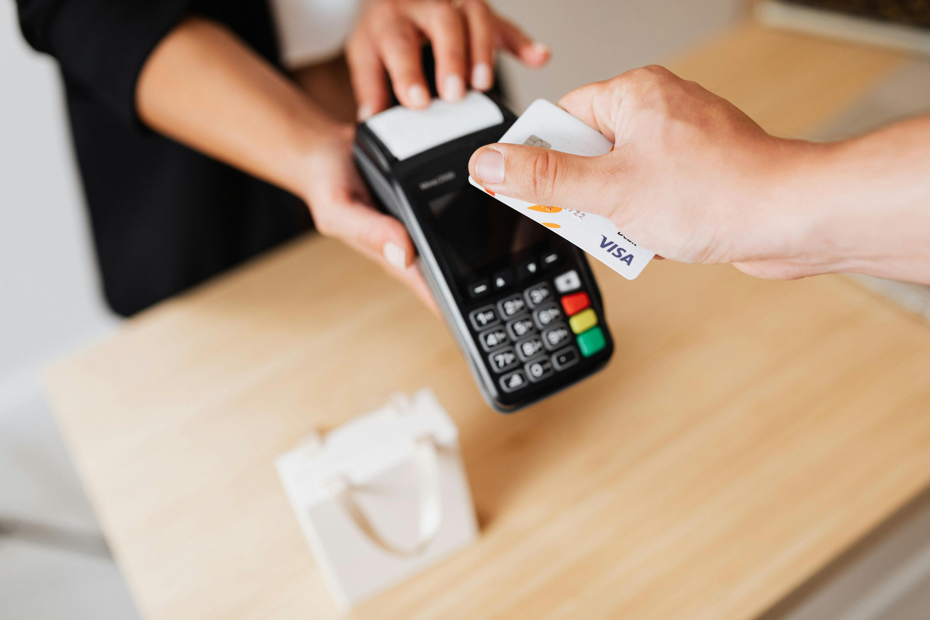 Hand inserting a credit card into a contactless payment terminal