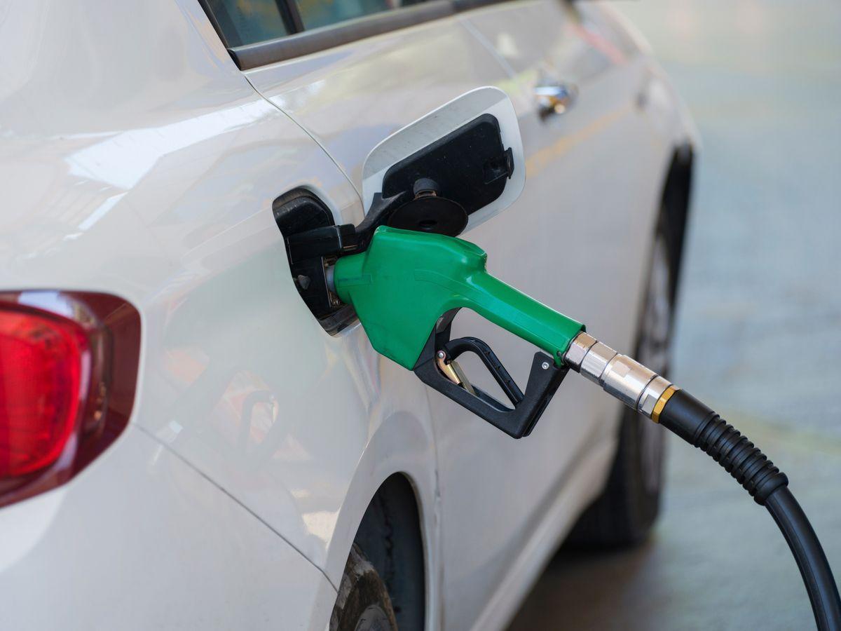 Green fuel nozzle refueling a car at a gas station — typical fuel stop on a Korea road trip
