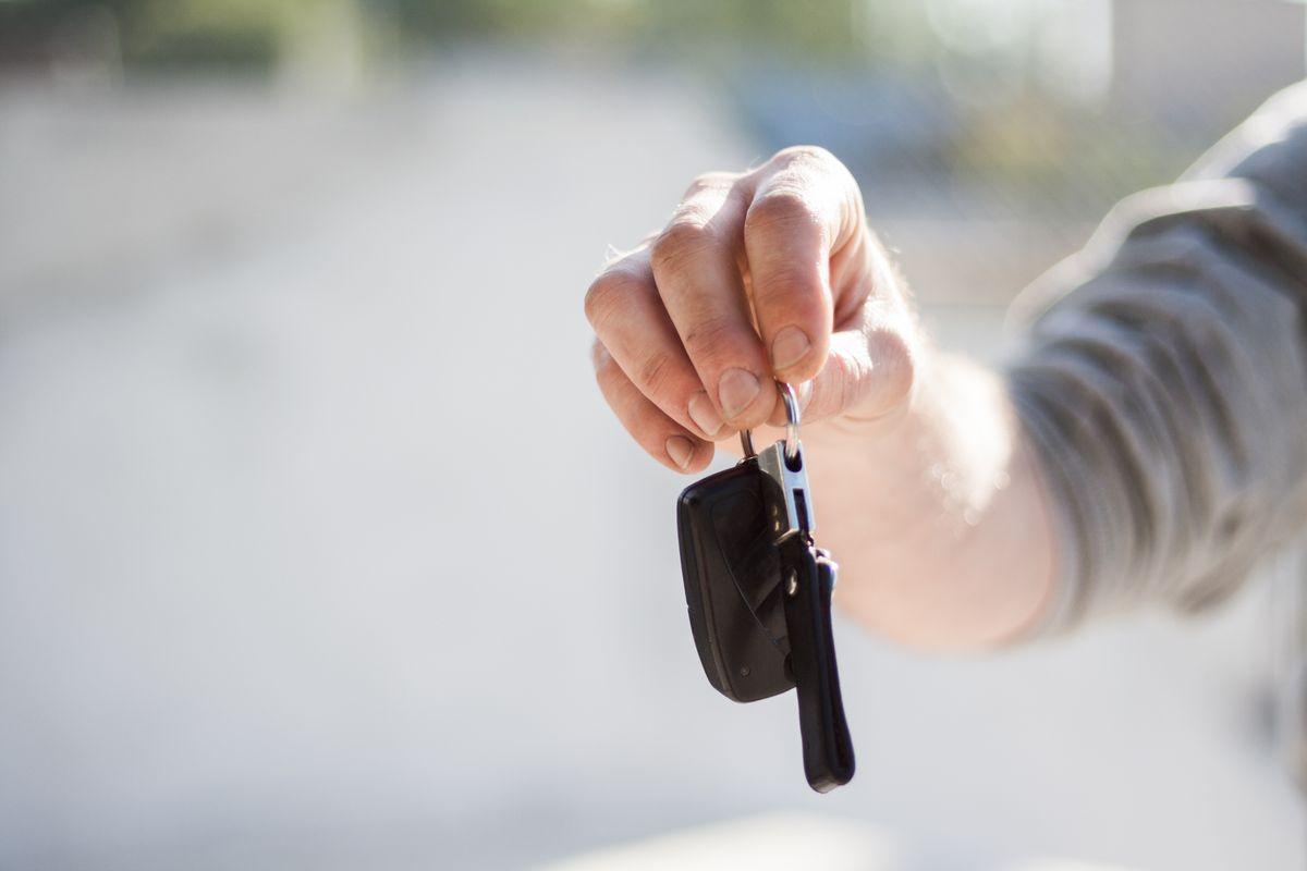 Hand handing over car keys at a rental desk, symbolizing the car rental process in Korea