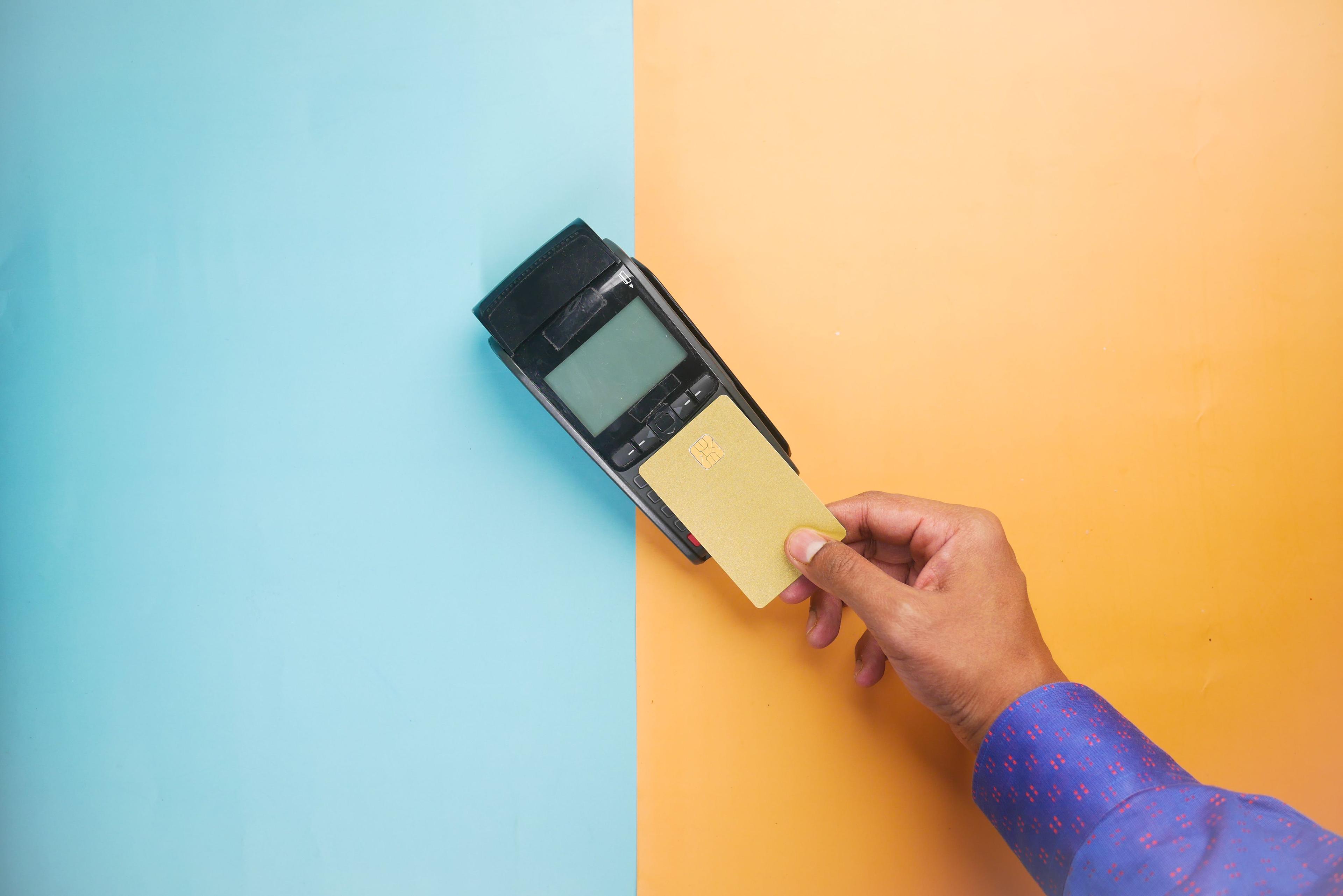 Hand tapping a credit card on a payment terminal to authorize a Korea rental car deposit hold