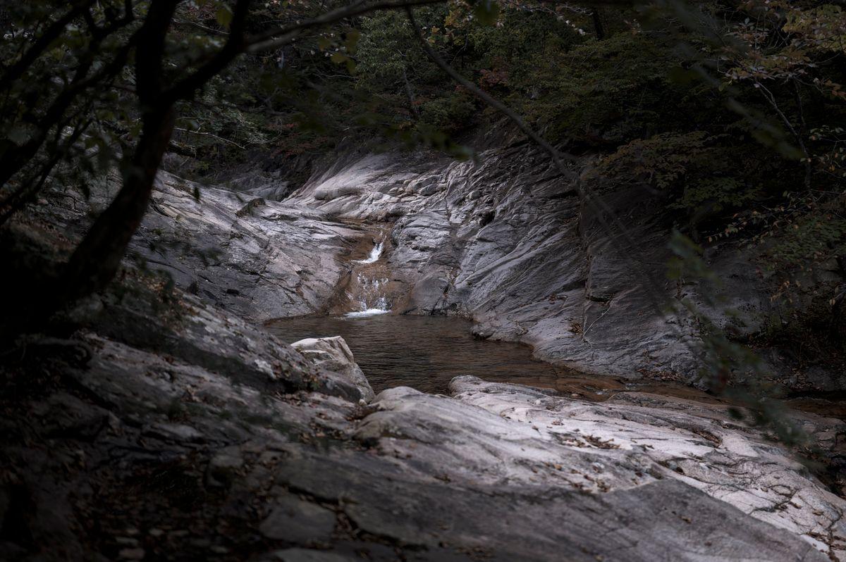 Rocky waterfall tumbling through dense green forest in Inje County, Gangwon Province, South Korea
