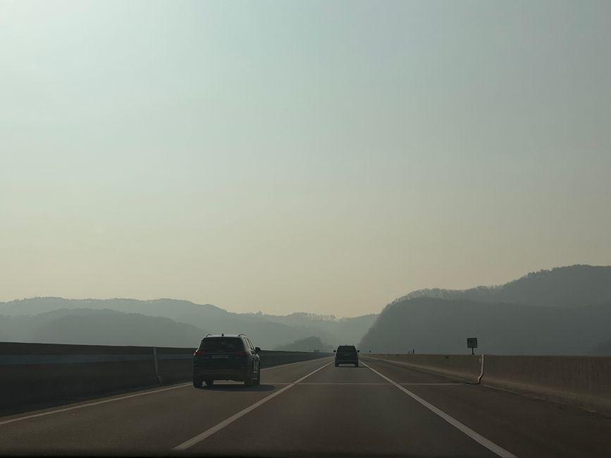 Tranquil two-lane highway through South Korean mountains under clear blue sky with forested slopes
