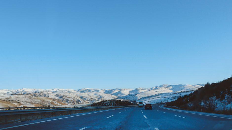 Aerial view of a highway through mountain terrain under clear blue sky