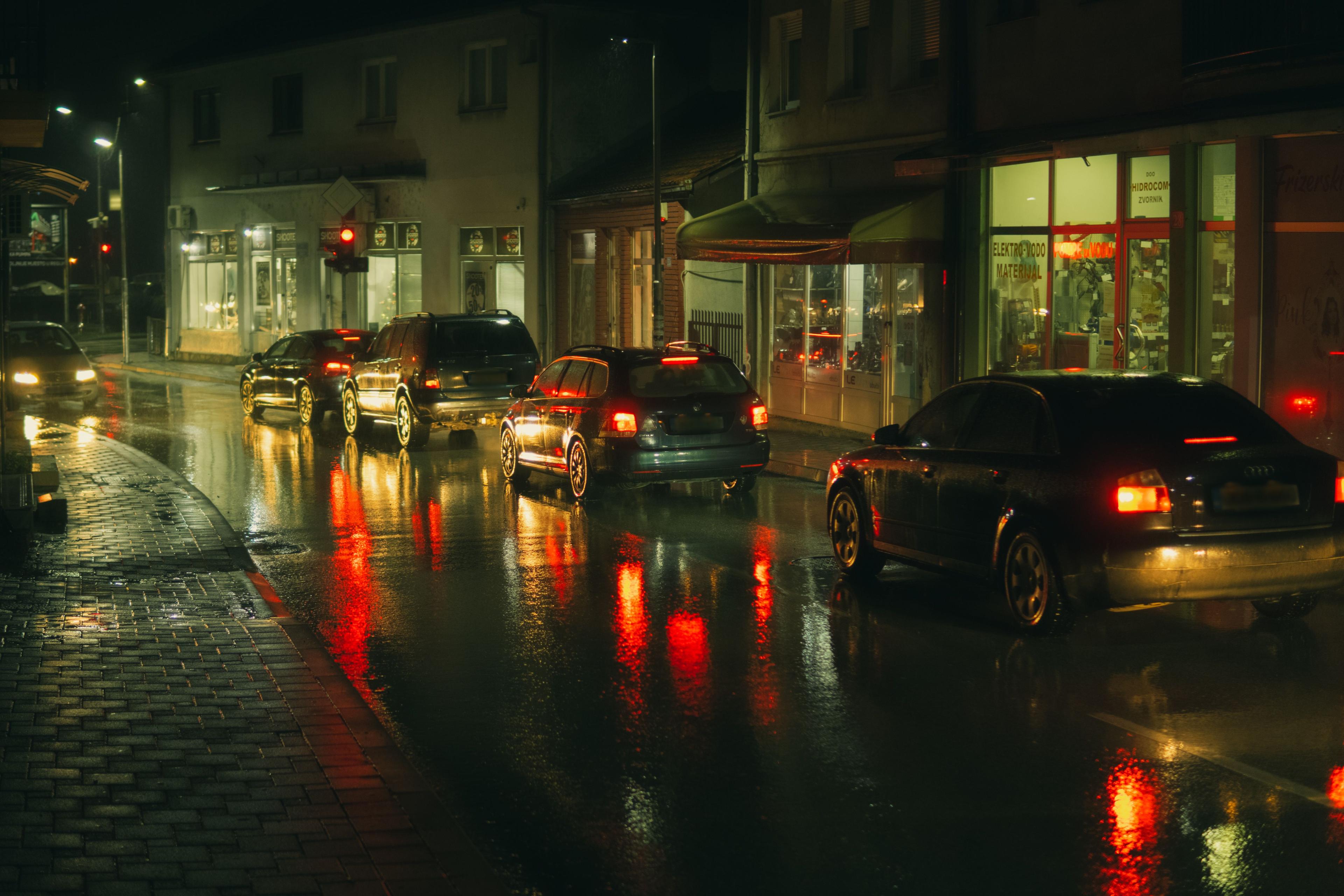Cars stopped with hazard lights on a wet road at night during a Korea storm
