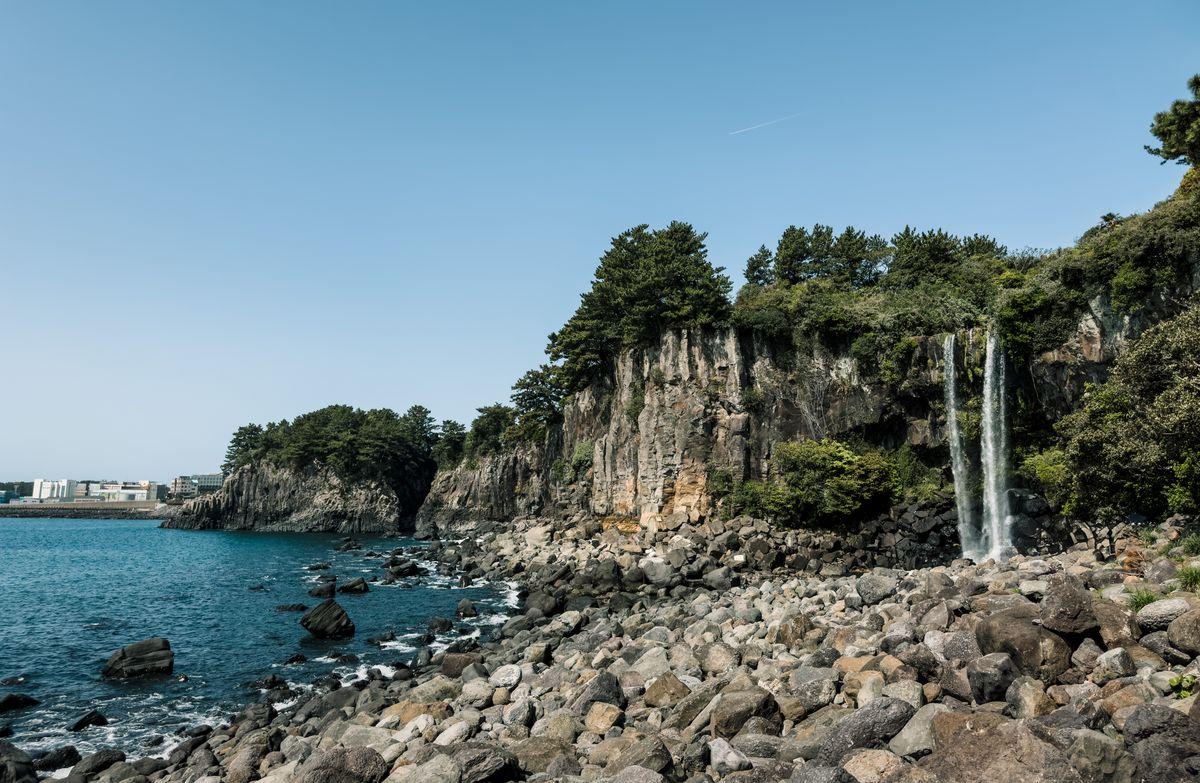 Jeongbang Waterfall in Jeju Island plunging directly into the sea from a rocky basalt cliff