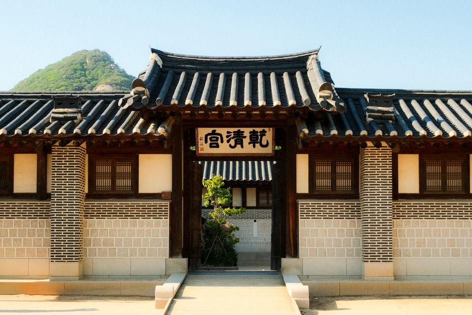 Traditional Korean fortress gate with wooden pillars set against a forested mountain backdrop at Mungyeong Saejae