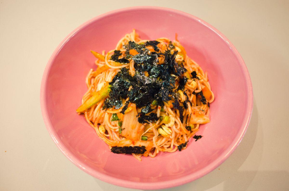 Korean bibim guksu — spicy mixed noodles with vegetables and crispy seaweed served on a plate