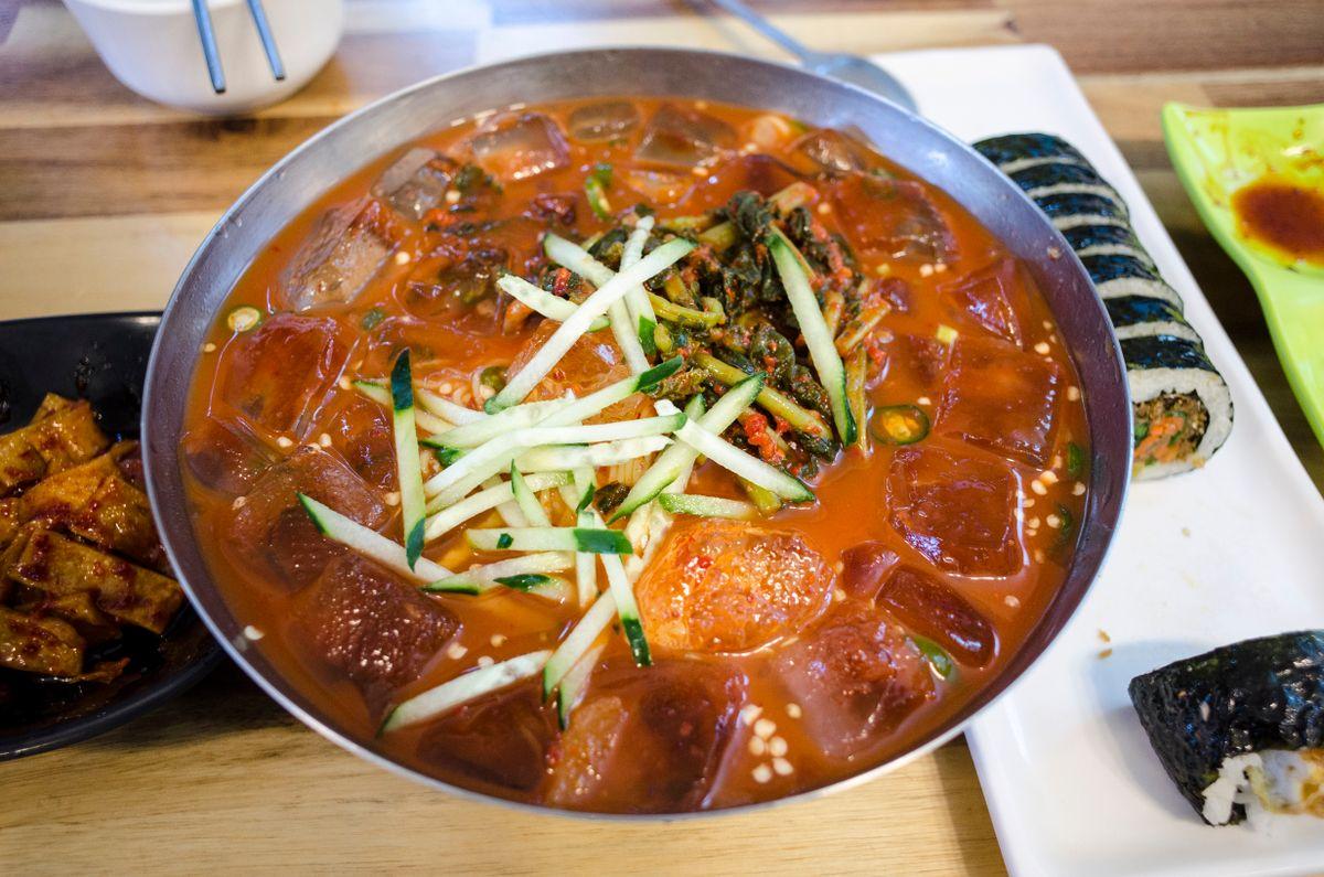 Traditional Korean naengmyeon served in a stainless steel silver bowl with side dishes