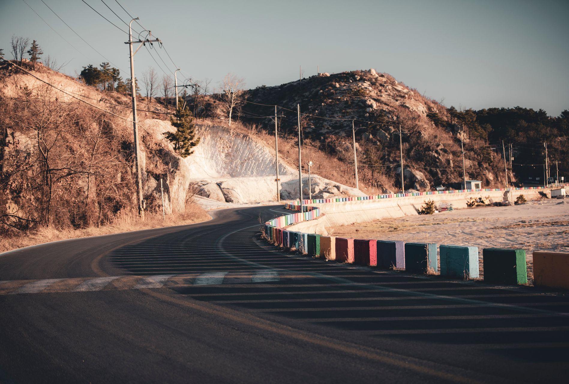 Winding mountain road with colorful barriers in Gangwon Province, South Korea, surrounded by green hills
