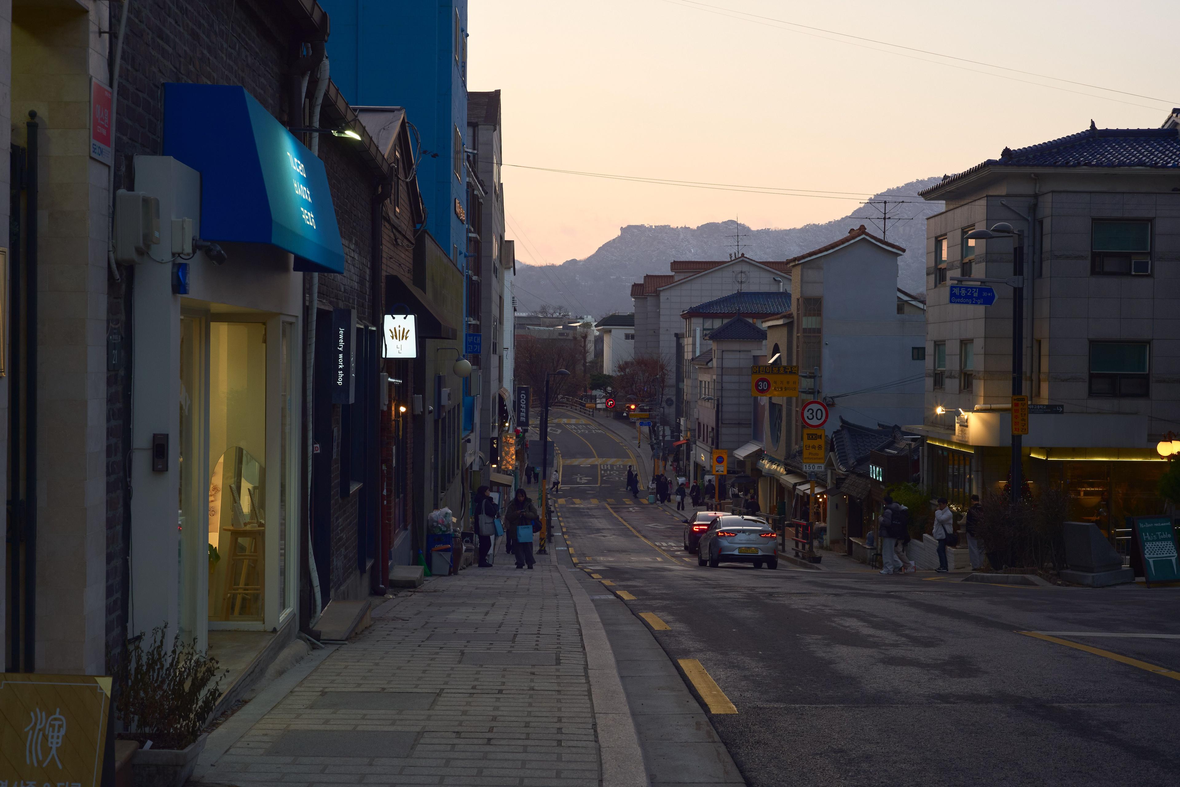 Evening street scene in Seoul traditional cultural district with mountain backdrop and local shops