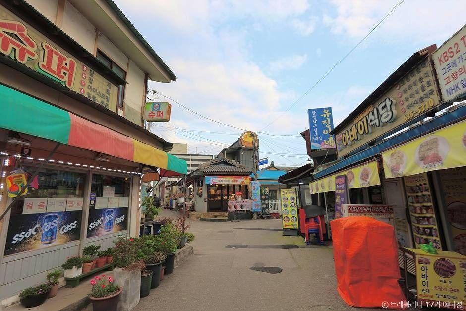 Row of small family-run restaurant stalls with handwritten signs in Abai Village's food alley, Sokcho