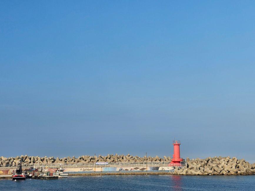 Red lighthouse surrounded by tetrapods at Ulsan Harbor under a clear blue sky on the East Sea coast